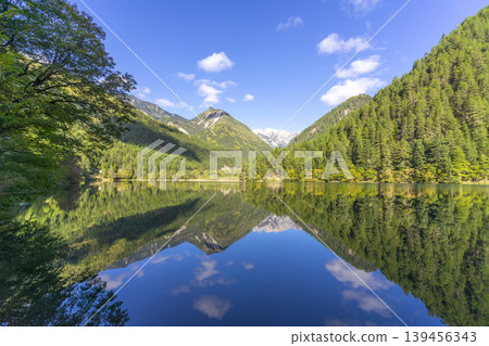 Amazing view of Mirror Lake with crystal clear water among mountains and evergreen woods in Jiuzhaigou nature reserve (Jiuzhai Valley National Park),China. Amazing view of Mirror Lake with crystal clear water among mountains and evergreen woods in Jiuzhaigou nature reserve (Jiuzhai Valley National Park),China. 139456343