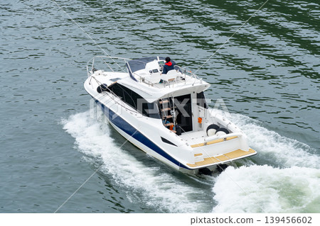An overhead view of a small cruiser boat navigating the water. An overhead view of a small cruiser boat navigating the water. 139456602