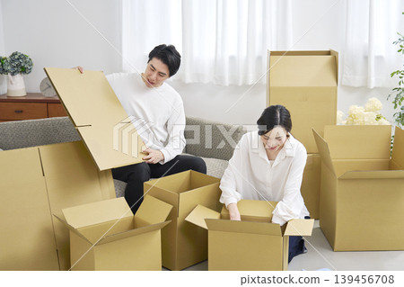 A couple packing cardboard boxes for their move. A couple packing cardboard boxes for their move. 139456708