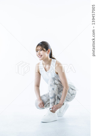 一位身穿運動服的年輕女子正在繫鞋帶 一位身穿運動服的年輕女子正在繫鞋帶 139457005