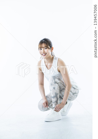 一位身穿運動服的年輕女子正在繫鞋帶 139457006