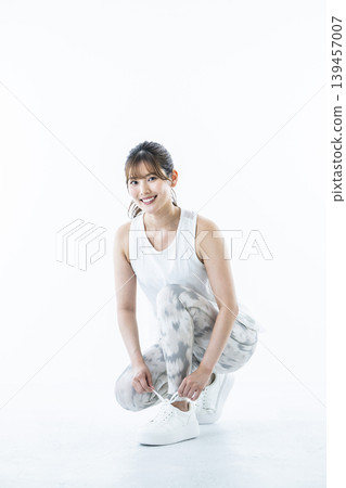 一位身穿運動服的年輕女子正在繫鞋帶 一位身穿運動服的年輕女子正在繫鞋帶 139457007