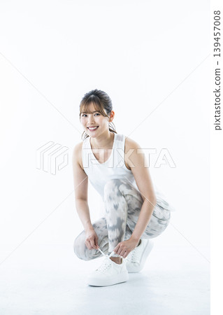 一位身穿運動服的年輕女子正在繫鞋帶 一位身穿運動服的年輕女子正在繫鞋帶 139457008