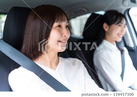 A woman smiling in the driver's seat; a passenger in the front seat; car sharing; car insurance. A woman smiling in the driver's seat; a passenger in the front seat; car sharing; car insurance. 139457300