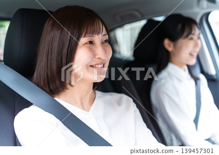A smiling woman driving a car with her friend in the passenger seat. (Driving Lifestyle) 139457301