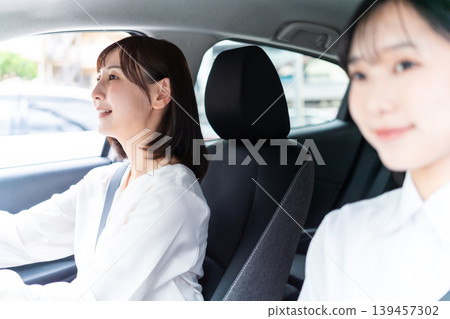 A smiling woman driving a car with her friend in the passenger seat. (Driving Lifestyle) A smiling woman driving a car with her friend in the passenger seat. (Driving Lifestyle) 139457302