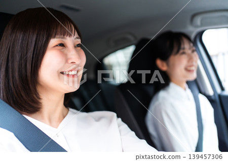 A smiling woman driving a car with her friend in the passenger seat. (Driving Lifestyle) A smiling woman driving a car with her friend in the passenger seat. (Driving Lifestyle) 139457306
