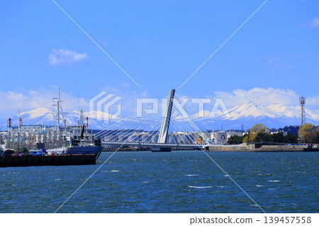 Hachinohe City: Coastal Industrial Zone and Hachitaro Bridge | A view of the snow-capped Hakkoda Mountains and Kushigamine Peak against a blue sky. Hachinohe City: Coastal Industrial Zone and Hachitaro Bridge | A view of the snow-capped Hakkoda Mountains and Kushigamine Peak against a blue sky. 139457558
