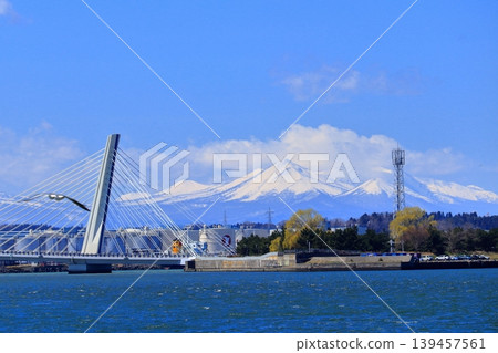 Hachinohe City: Coastal Industrial Zone and Hachitaro Bridge | A view of the snow-capped Hakkoda Mountains and Kushigamine Peak against a blue sky. Hachinohe City: Coastal Industrial Zone and Hachitaro Bridge | A view of the snow-capped Hakkoda Mountains and Kushigamine Peak against a blue sky. 139457561