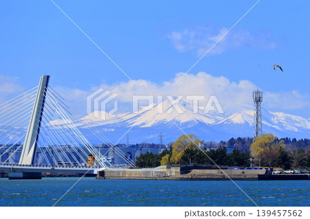 Hachinohe City: Coastal Industrial Zone and Hachitaro Bridge | A view of the snow-capped Hakkoda Mountains and Kushigamine Peak against a blue sky. Hachinohe City: Coastal Industrial Zone and Hachitaro Bridge | A view of the snow-capped Hakkoda Mountains and Kushigamine Peak against a blue sky. 139457562