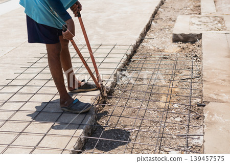 Construction worker uses heavy duty orange bolt cutters to trim steel rebar mesh. Construction worker uses heavy duty orange bolt cutters to trim steel rebar mesh. 139457575