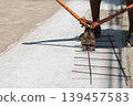 Construction worker uses heavy duty orange bolt cutters to trim steel rebar mesh. 139457583