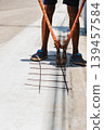 Construction worker uses heavy duty orange bolt cutters to trim steel rebar mesh. 139457584
