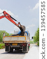 An orange crawler excavator digs a paved residential road for maintenance. 139457585