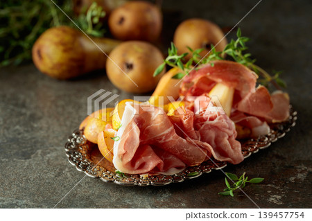 Prosciutto with pears and thyme on a silver tray. Prosciutto with pears and thyme on a silver tray. 139457754