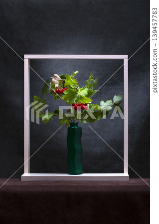 A branch of red viburnum in a vase and a wooden frame 139457783