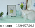 Skincare products and cosmetic bag with decorative flowers and frame on a mint green cloth. 139457898