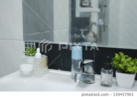 Aesthetic bathroom sink counter with skincare bottles, potted succulents, and clean tiles. Aesthetic bathroom sink counter with skincare bottles, potted succulents, and clean tiles. 139457901