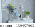 Minimalist bathroom decor with assorted toiletries and floral arrangement against a tiled wall. 139457903