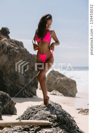 Woman in pink swimwear posing on beach, enjoying summer vibes Woman in pink swimwear posing on beach, enjoying summer vibes 139458032