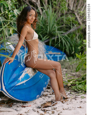 Smiling tanned woman in bikini sitting on boat. Fashionable woman Smiling tanned woman in bikini sitting on boat. Fashionable woman 139458034