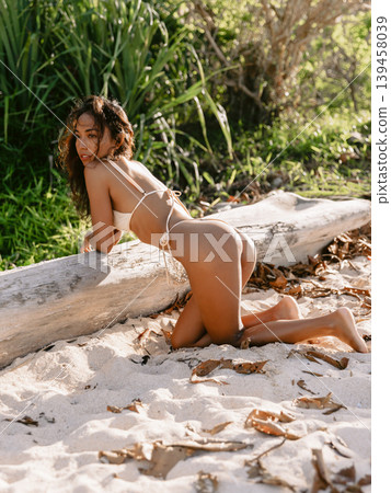 Asian woman in bikini at tropical sunny beach. Lady with slim body posing at ocean coastline Asian woman in bikini at tropical sunny beach. Lady with slim body posing at ocean coastline 139458039