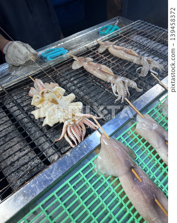 Filming vendors skillfully preparing grilled squid at a night market in Taichung. Filming vendors skillfully preparing grilled squid at a night market in Taichung. 139458372