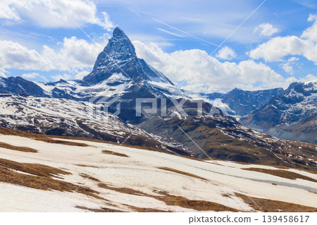 Scenic view on snowy Matterhorn mountain peak in sunny day with blue sky in Switzerland. Beautiful nature background of Swiss Alps covered with snow. Famous travel destination Scenic view on snowy Matterhorn mountain peak in sunny day with blue sky in Switzerland. Beautiful nature background of Swiss Alps covered with snow. Famous travel destination 139458617