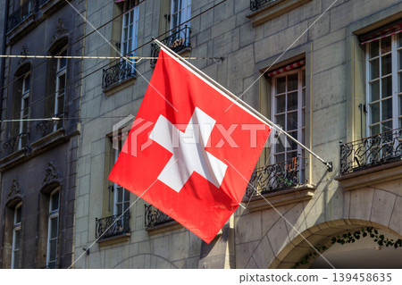Red Swiss flag hanging from building facade Red Swiss flag hanging from building facade 139458635