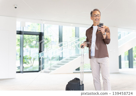 一位老年男性旅客入住飯店,透過智慧型手機預訂。 一位老年男性旅客入住飯店,透過智慧型手機預訂。 139458724