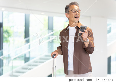 一位老年男性旅客入住飯店,透過智慧型手機預訂。 一位老年男性旅客入住飯店,透過智慧型手機預訂。 139458725