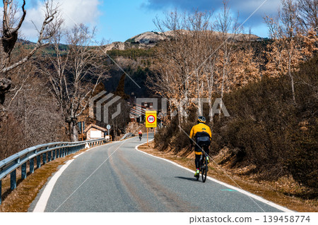Cyclist riding rural road through autumn mountains Cyclist riding rural road through autumn mountains 139458774