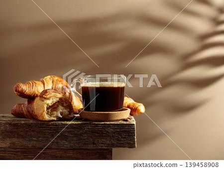 Black coffee with croissants on an old wooden table. Black coffee with croissants on an old wooden table. 139458908