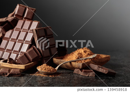 Broken dark chocolate bar and cocoa powder on a black background. 139458918