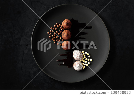 Chocolate truffles on a black plate. 139458933