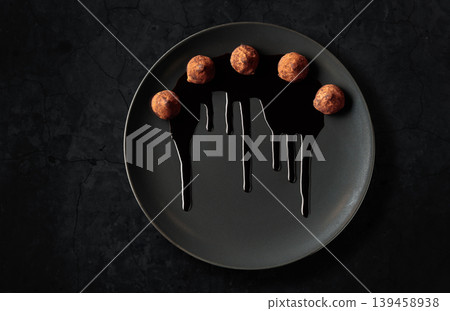 Chocolate truffles on a black plate. 139458938