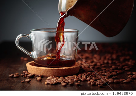 Black coffee is poured into a glass cup. Black coffee is poured into a glass cup. 139458970