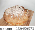 Homemade artisan sourdough bread on a wooden cutting board on a white background. 139459573
