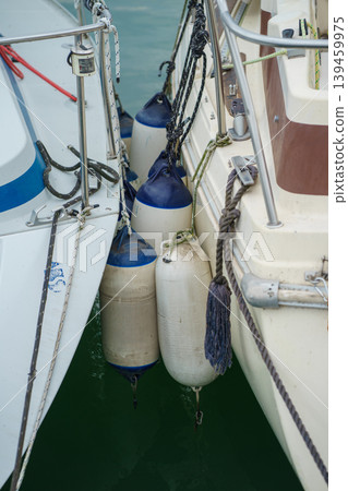 Close-up of boat fenders protecting hulls between docked vessels, marine safety equipment, harbor detail and nautical maintenance concept 139459975