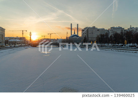 Winter City River Sunset With Snow-Covered Embankment And Urban Skyline Winter City River Sunset With Snow-Covered Embankment And Urban Skyline 139460025