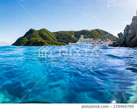 一張半淹沒在水下的阿卡島阿卡海灘照片。遠處有一艘渡輪駛過。阿卡海灘(真島濱),慶良間群島,島尻郡,沖繩縣 一張半淹沒在水下的阿卡島阿卡海灘照片。遠處有一艘渡輪駛過。阿卡海灘(真島濱),慶良間群島,島尻郡,沖繩縣 139460769