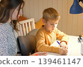 A mother helping her son with his studies. Homework assistance. Warm lighting. A cozy atmosphere for family learning. A focused student's pose. A scene of studying before bed. Space for text. Banner. 139461147