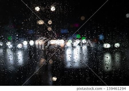 Rain on Window at Night with Blurred City Lights. Moody Urban Background. Raindrops Rain on Window at Night with Blurred City Lights. Moody Urban Background. Raindrops 139461294