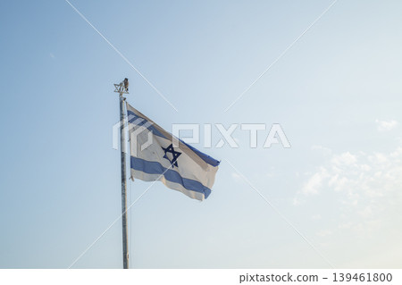 [Jerusalem] The Israeli flag flies against the clear evening sky at the Mount of Olives viewpoint. 139461800