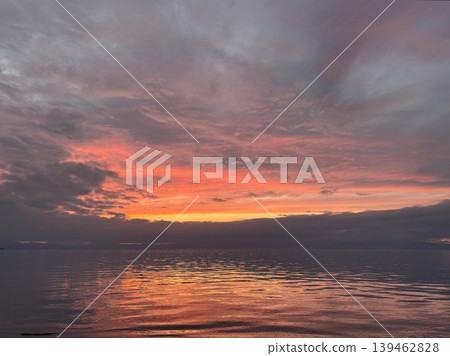The dramatic gradient of the sunset and its reflection on the calm water surface. 139462828