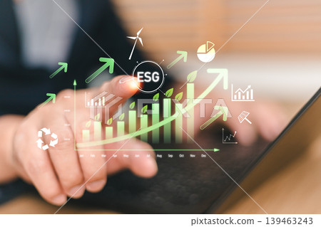 Businessman pointing at ESG virtual screen with growing green business graph and icons. Concept of sustainable investment, environmental social and corporate governance for long term growth Businessman pointing at ESG virtual screen with growing green business graph and icons. Concept of sustainable investment, environmental social and corporate governance for long term growth 139463243