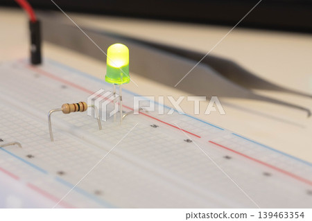 Green LED with resistor on breadboard, simple electronics project Green LED with resistor on breadboard, simple electronics project 139463354