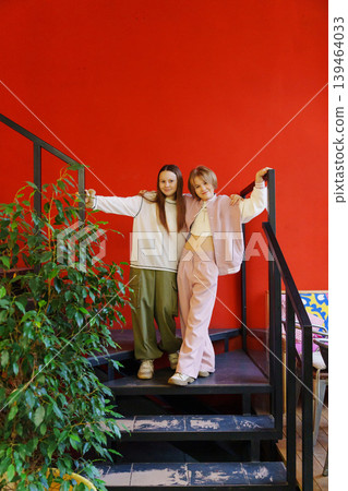 Girls posing on stairs in a cozy indoor space with red wall 139464033