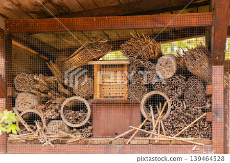 Insect hotel is made from wood and natural materials. It is full of sticks, leaves, and hollow tubes. This setup serves as a habitat for beneficial insects in a garden Insect hotel is made from wood and natural materials. It is full of sticks, leaves, and hollow tubes. This setup serves as a habitat for beneficial insects in a garden 139464528