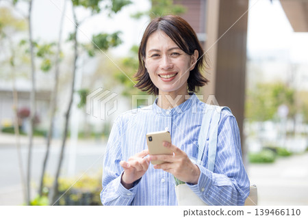 Middle women who operate smartphone outdoors 139466110